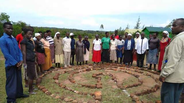A group of learners standing round a spiral garden they have just laid out in stone